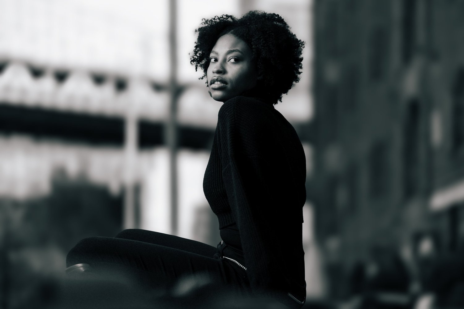 Woman stands for a portrait in a dark outfit outdoors.